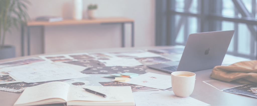 Werktafel met laptop, notities, schetsen en creatieve materialen die strategisch denken, positionering en innovatieontwikkeling ondersteunen.